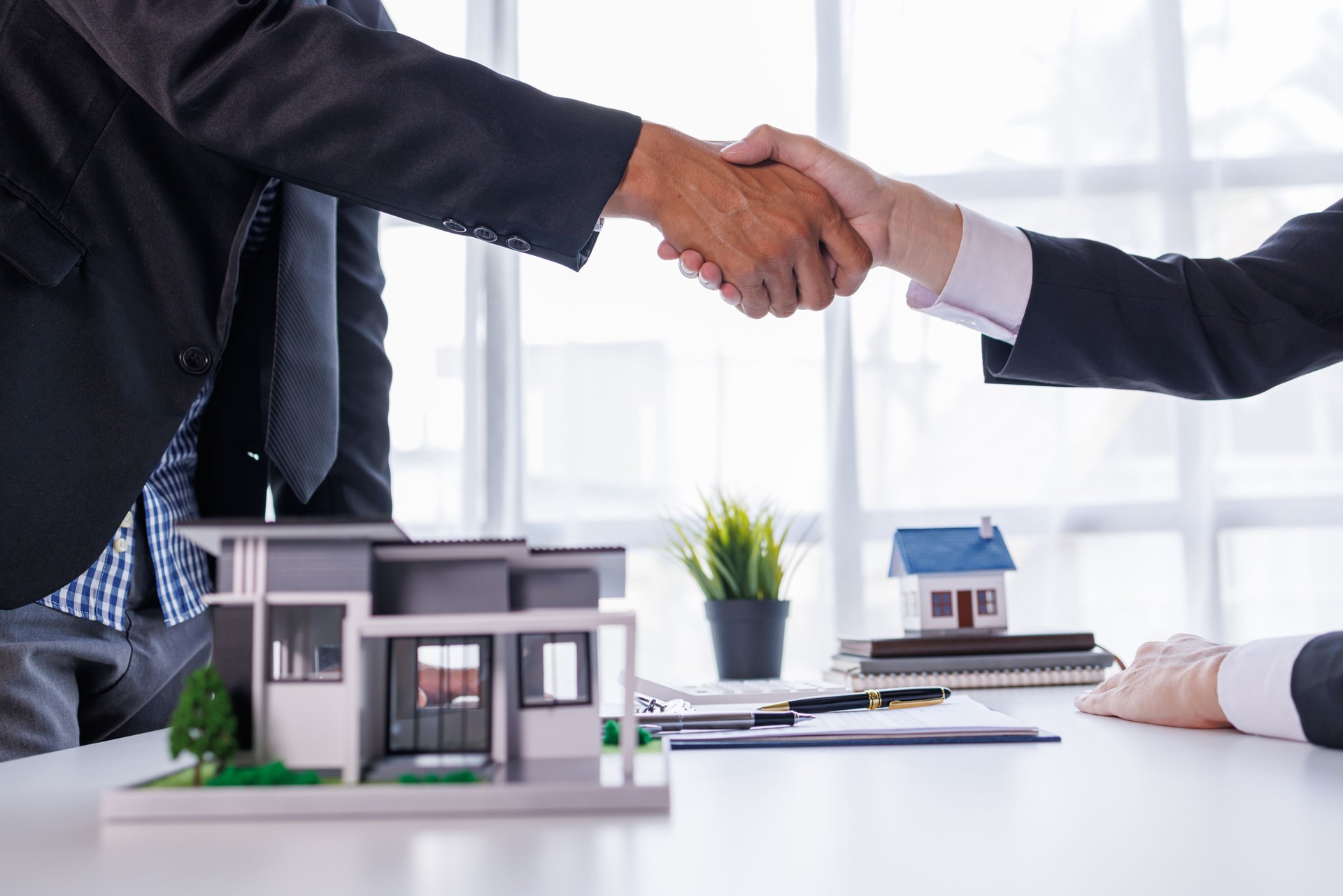 Handshake Real estate brokerage agent Deliver a sample of a model house to the customer, mortgage loan agreement Making lease and buy and sell house And contract home insurance mortgage loan concept