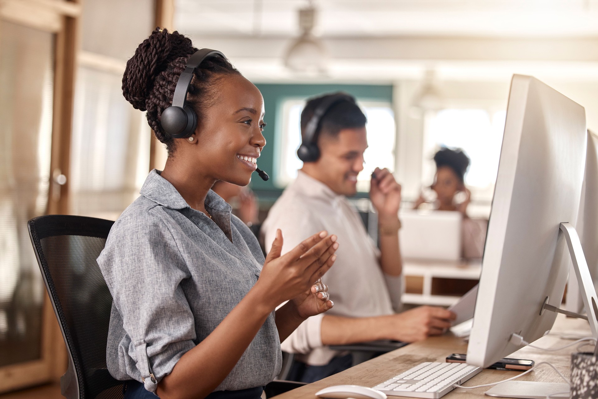 Call center, woman and smile at computer for telemarketing, sales and global support. Professional female consultant or agent with a headset and team for customer service, crm and help desk advice
