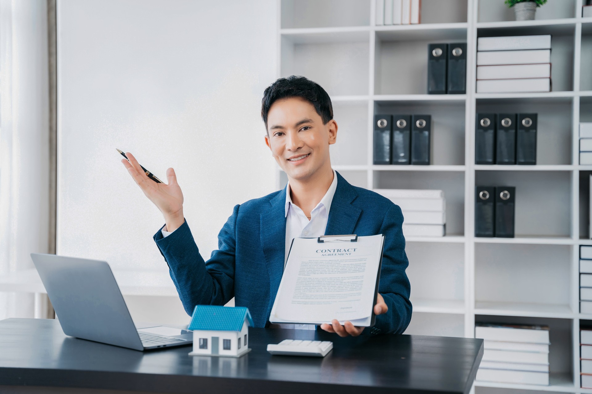 Buying a home or insurance deal, an insurance agent pointing a pen to those interested in renting a house, a contract, signing an Home buying agreement in office