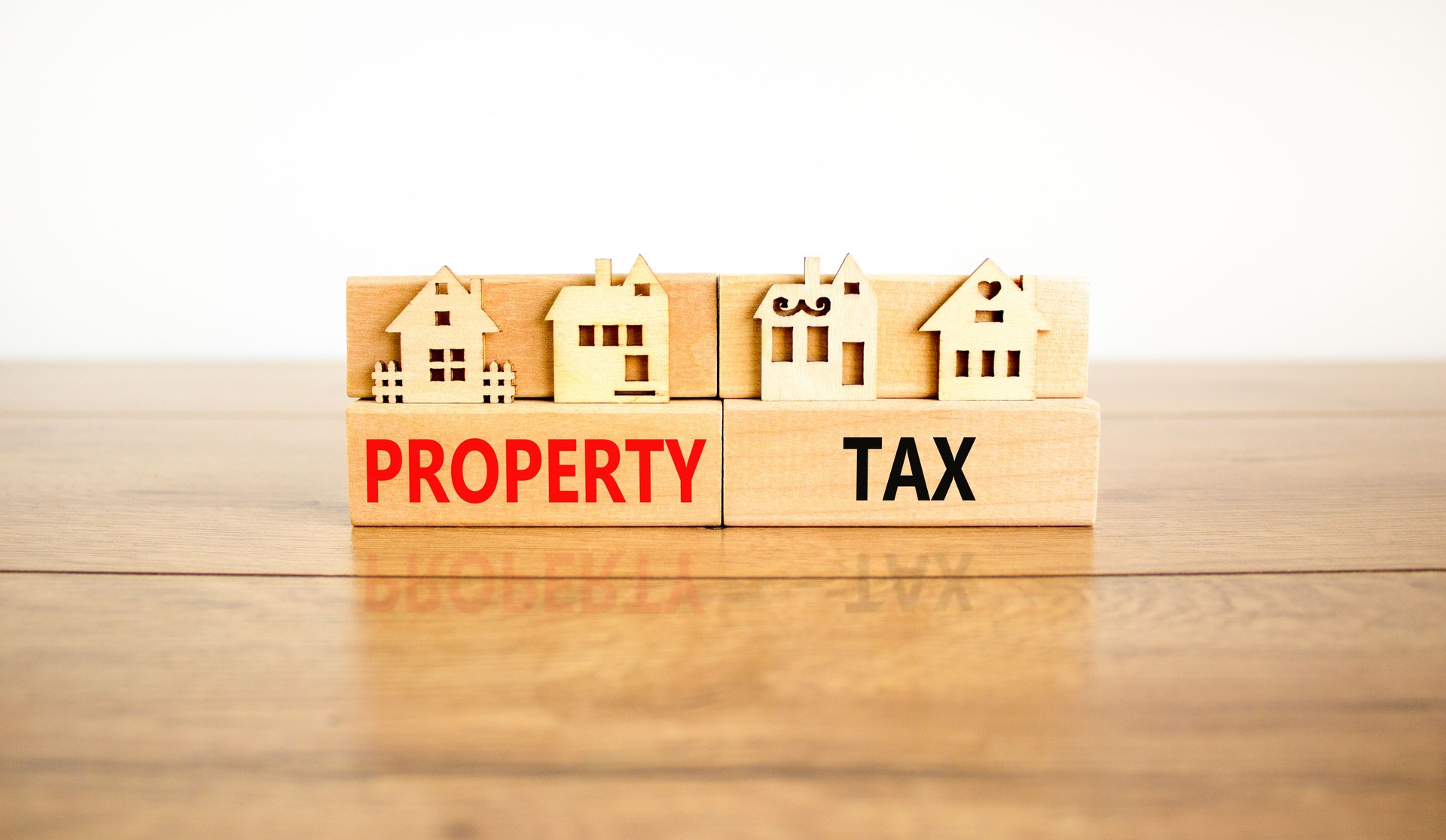 Property tax symbol. Concept words Property tax on wooden blocks. Beautiful wooden table white background. House models on wooden blocks. Business and property tax concept. Copy space.